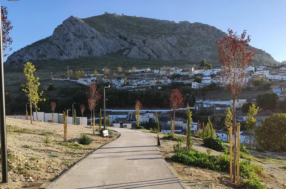 La Peña de Martos, gran mole rocosa que se alza sobre las casas blancas de Martos, vista desde un parque con árboles jóvenes
