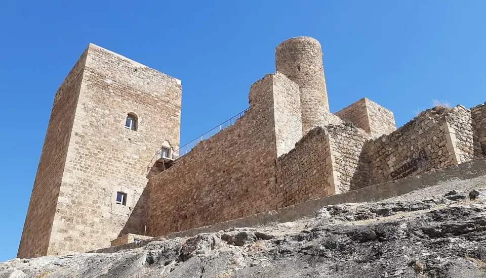 Torres y lienzos de muralla del castillo de La Guardia de Jaén sobre la roca, contra un cielo azul