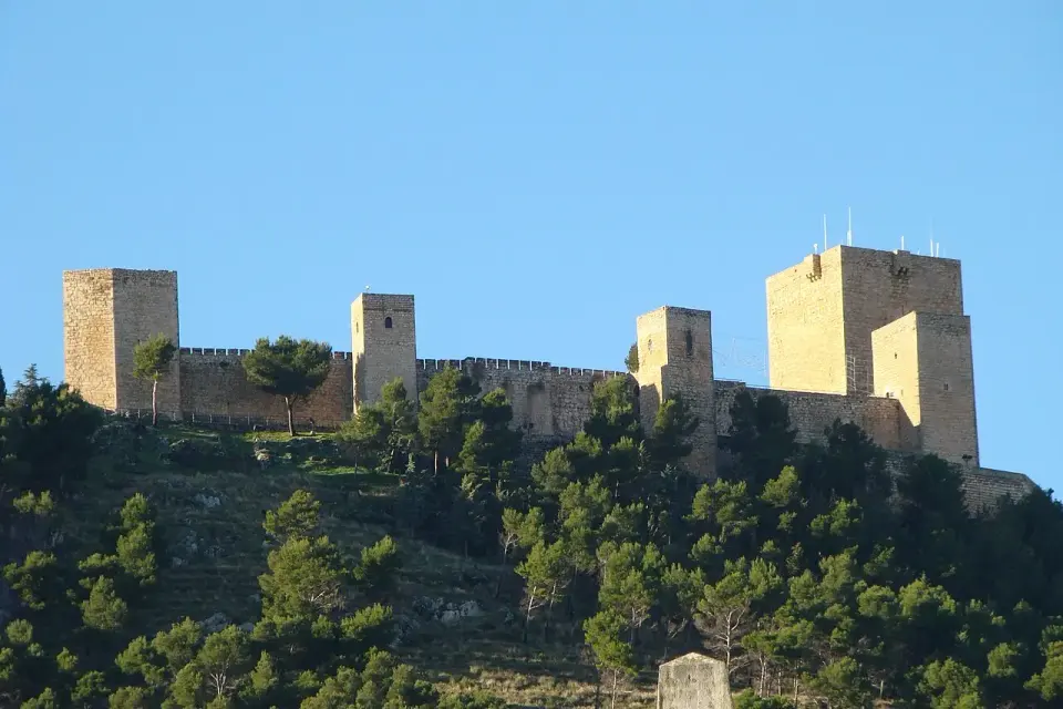 El castillo de Santa Catalina, con sus torres cuadradas, en lo alto de un cerro cubierto de pinos sobre Jaén