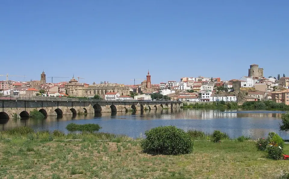 Alba de Tormes vista desde la orilla del río, con el puente de piedra de muchos arcos, las torres de sus iglesias y la torre del castillo