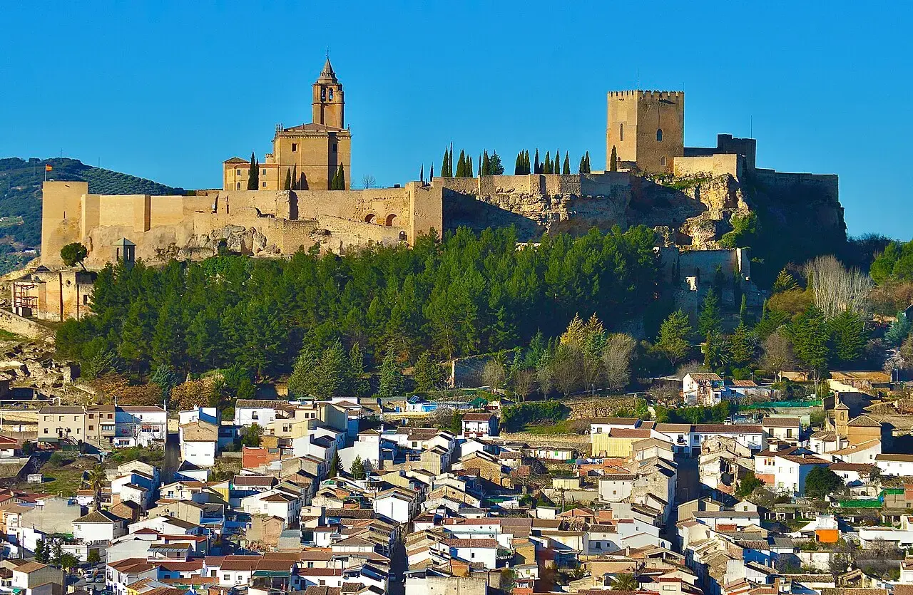La fortaleza de La Mota, con sus murallas y torres doradas sobre un cerro arbolado, y el caserío blanco de Alcalá la Real a sus pies