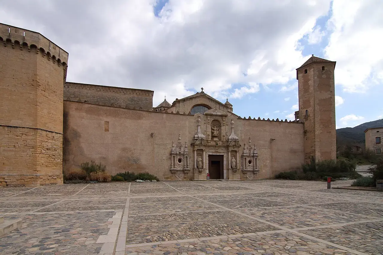 Puerta Real del monasterio de Poblet flanqueada por dos torres almenadas, con la plaza empedrada delante