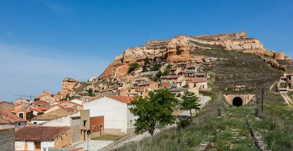 Casas de San Esteban de Gormaz al pie de un cerro de roca rojiza, con un antiguo túnel ferroviario en la ladera