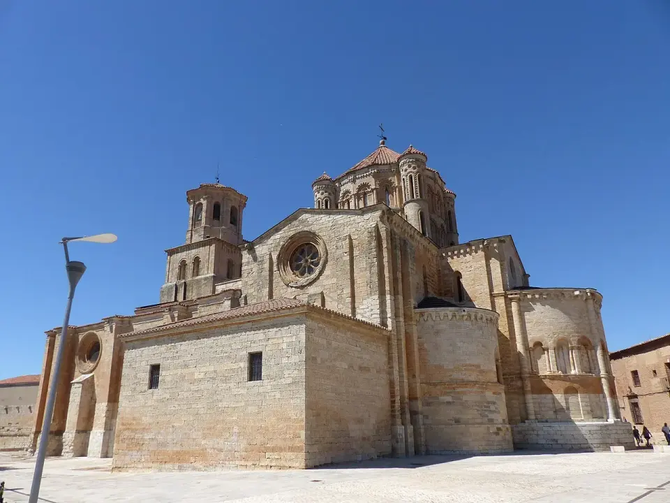 Colegiata románica de Santa María la Mayor de Toro con su cimborrio y ábsides de piedra dorada bajo un cielo azul