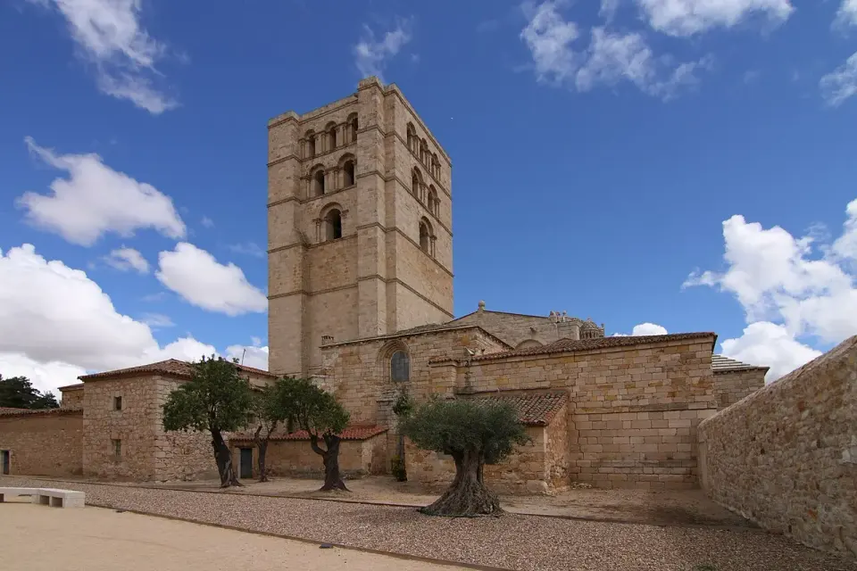 Torre de la catedral de Zamora vista desde la muralla, con olivos en primer plano y nubes blancas