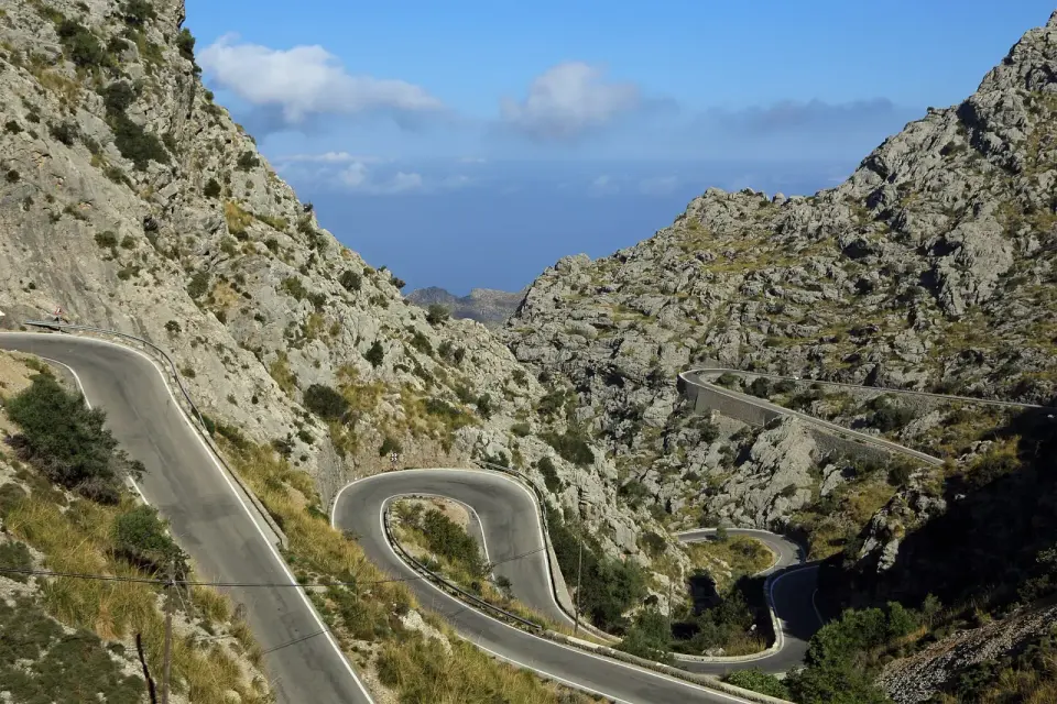 Horquillas de la carretera MA-2141 bajando entre montañas de roca caliza hacia Sa Calobra, con el mar al fondo