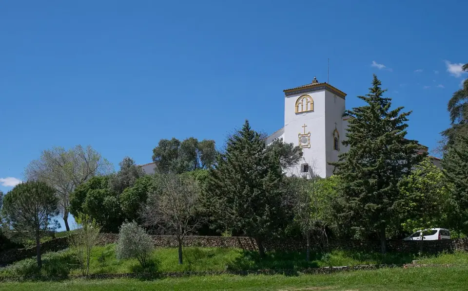 Ermita blanca de la Reina de los Ángeles entre árboles en la Peña de Arias Montano, en Alájar