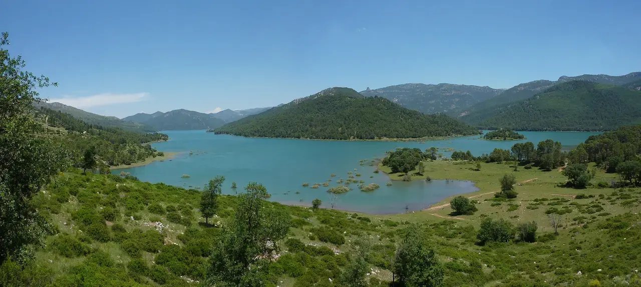 Panorámica del embalse del Tranco de Beas, de aguas turquesas entre colinas de pinar y sierras al fondo