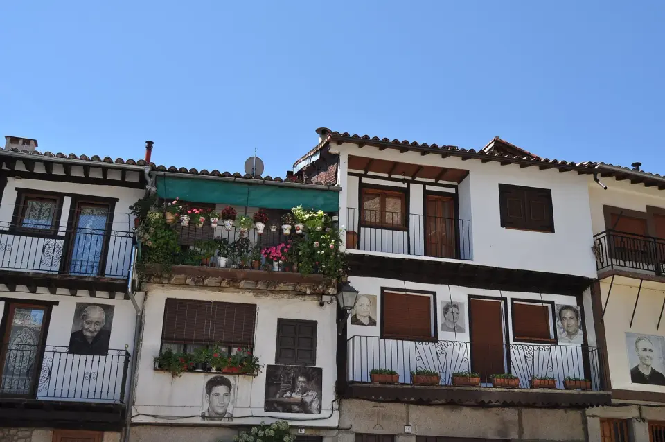 Fachadas de Mogarraz con balcones de madera y retratos pintados de antiguos vecinos junto a las puertas y ventanas
