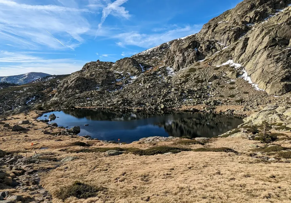 La Laguna Grande de Peñalara, de aguas oscuras, rodeada de pastos secos y paredes de granito con restos de nieve