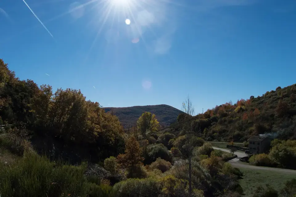 Valle de la Sierra de la Demanda con bosque de colores otoñales, matorral y montes suaves bajo un cielo despejado