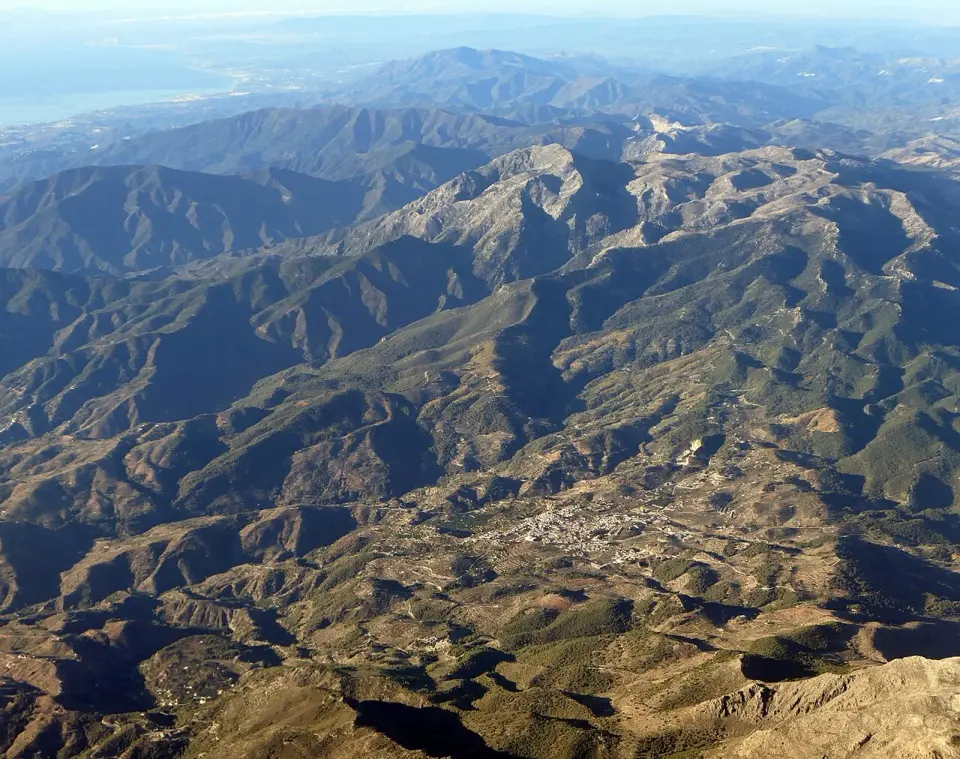 Vista aérea de Yunquera rodeada de sierras, con las montañas de la Sierra de las Nieves y la costa al fondo