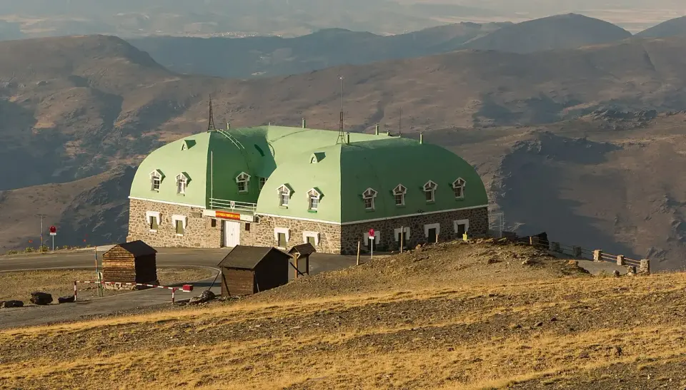 Refugio militar Capitán Cobo, edificio de piedra con tejado verde, al final de la carretera de la Hoya de la Mora con luz de tarde