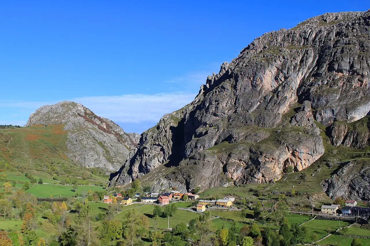El pueblo de Valle de Lago entre prados verdes, a los pies de grandes paredes de roca en el parque natural de Somiedo