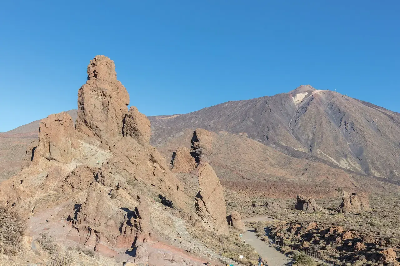 Los Roques de García en primer plano, con formas de lava erosionada, y el volcán Teide al fondo bajo un cielo azul
