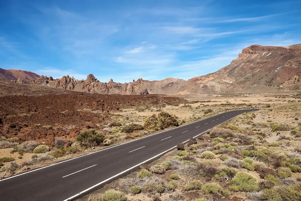 La carretera TF-21 cruzando la caldera de Las Cañadas entre coladas de lava y matorral, con los Roques de García y la pared de la caldera al fondo