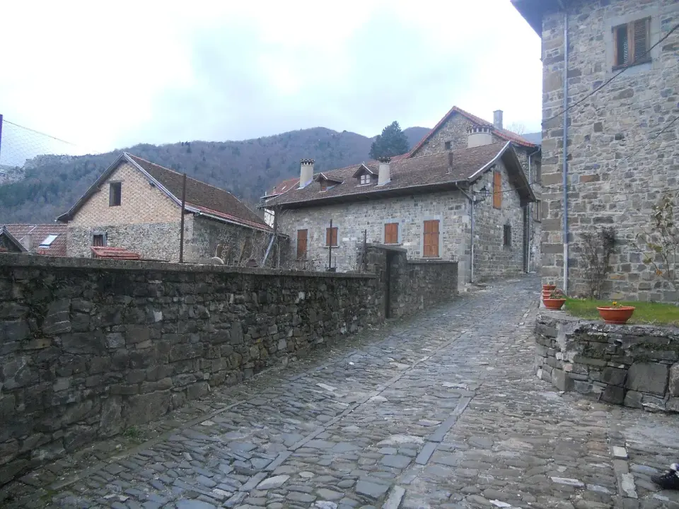 Calle empedrada de Isaba con casas de piedra y tejados a dos aguas, con montañas boscosas detrás