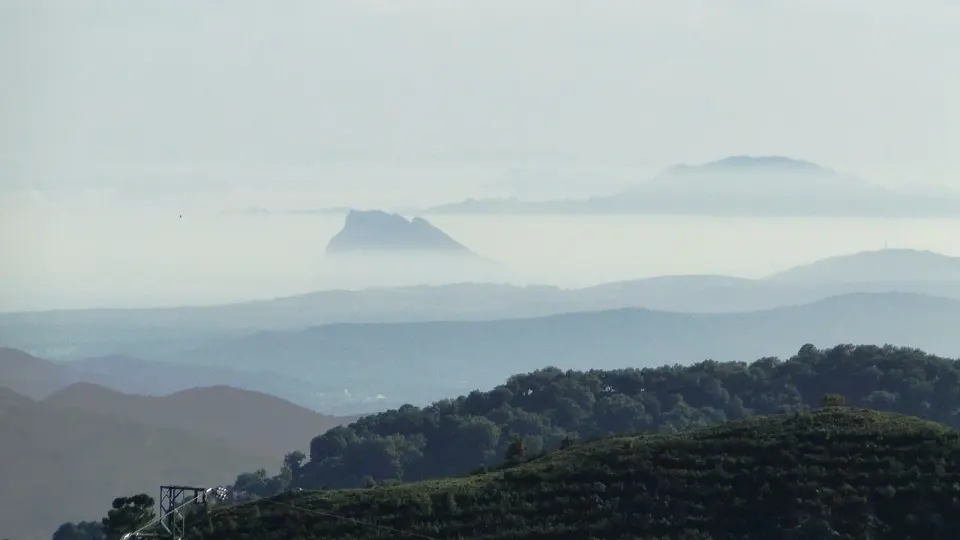 Peñón de Gibraltar recortado entre la bruma, sobre sierras encadenadas, visto desde el mirador del Genal en la carretera de Algatocín a Gaucín