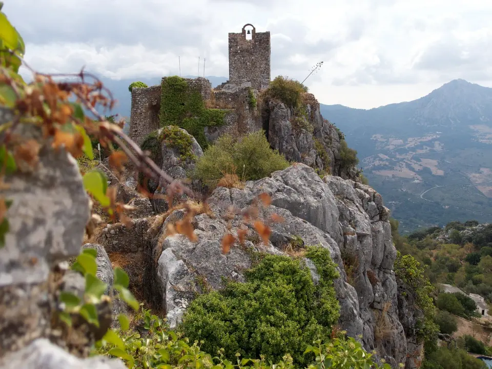 Torre del homenaje y murallas del castillo del Águila de Gaucín sobre un farallón de roca, con la sierra al fondo