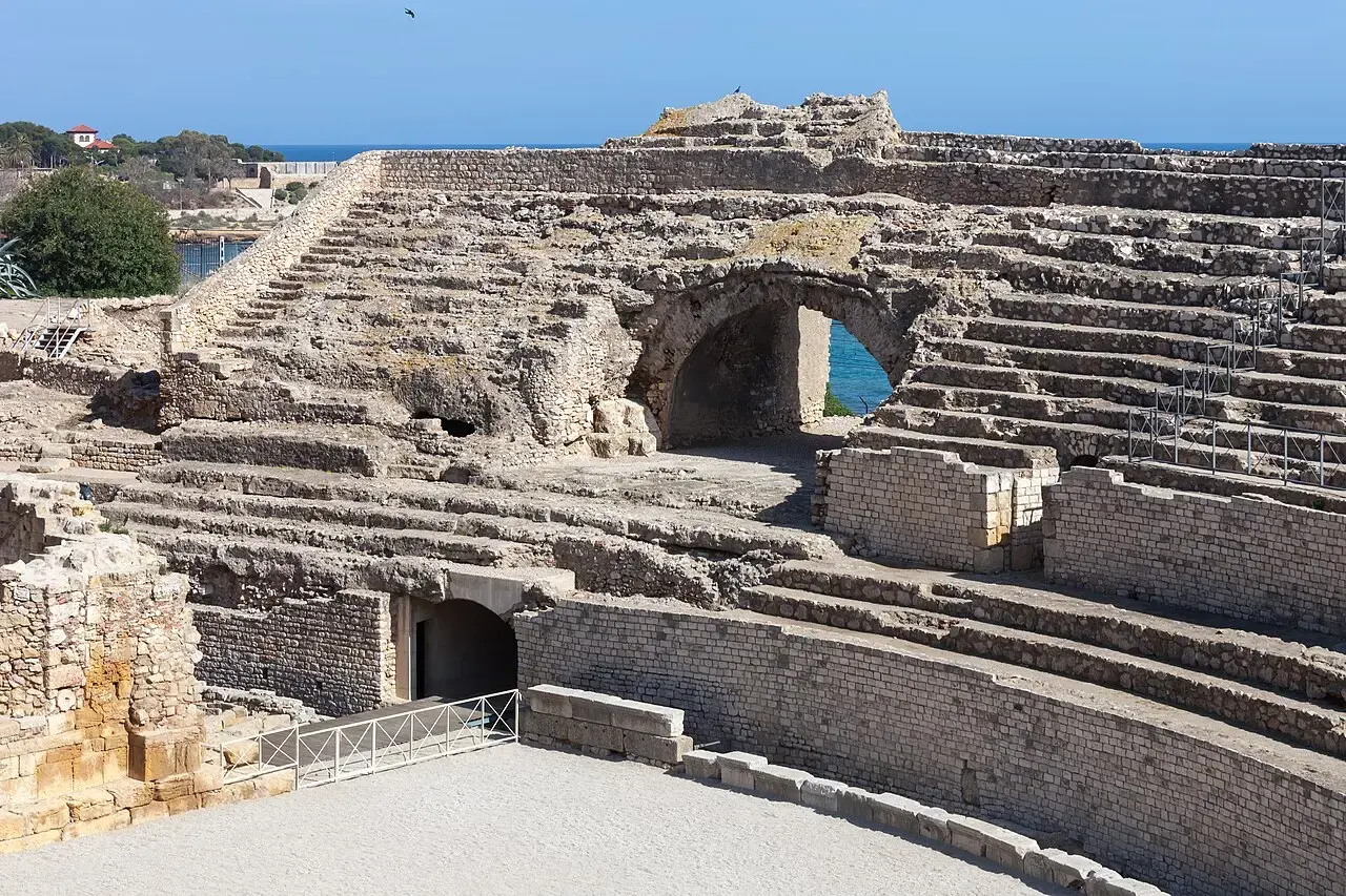 Graderíos y galerías de piedra del anfiteatro romano de Tarragona, con un arco abierto al mar Mediterráneo