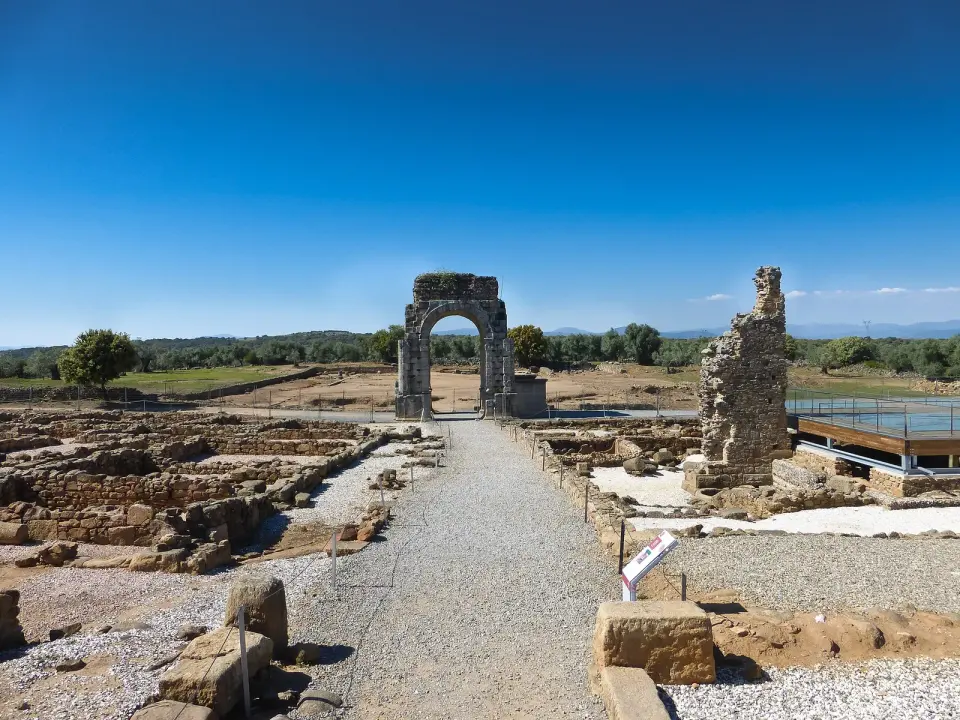 Arco romano de cuatro caras de Cáparra entre los restos de la antigua ciudad, con la calzada de la Vía de la Plata en primer plano