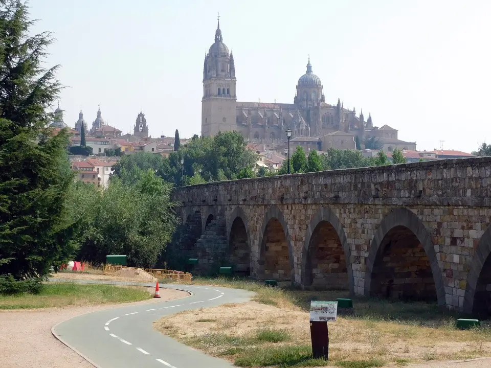 Puente romano de piedra sobre el río Tormes con las torres de las catedrales de Salamanca al fondo