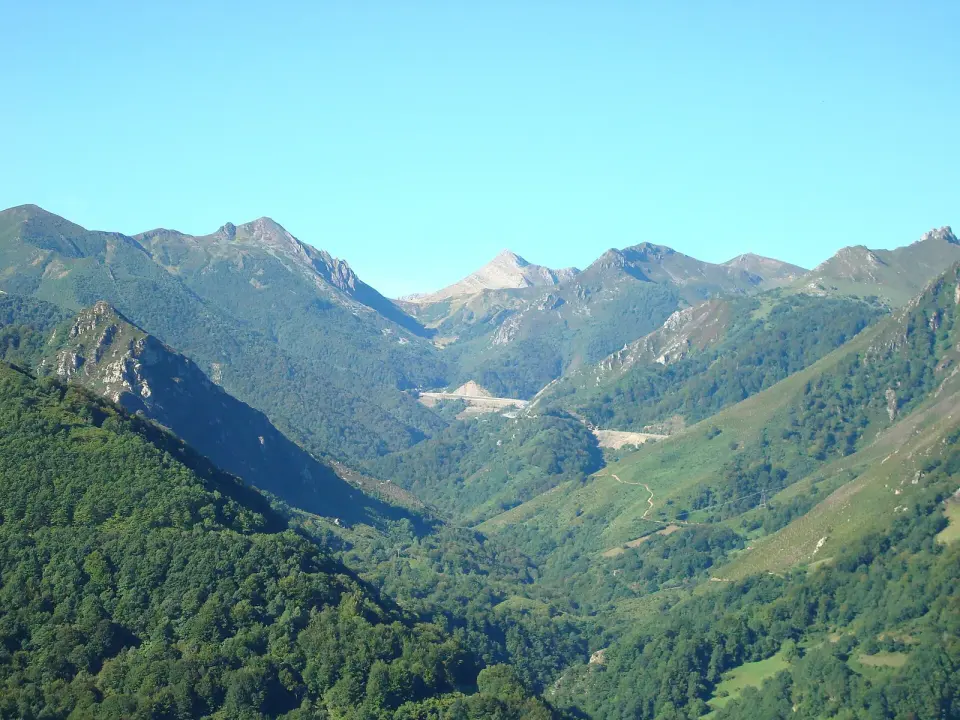 Valle verde y cumbres de la cordillera Cantábrica en la bajada del puerto de Pajares hacia Asturias